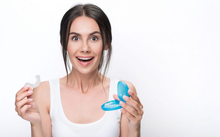 Happy young woman presenting clear aligners